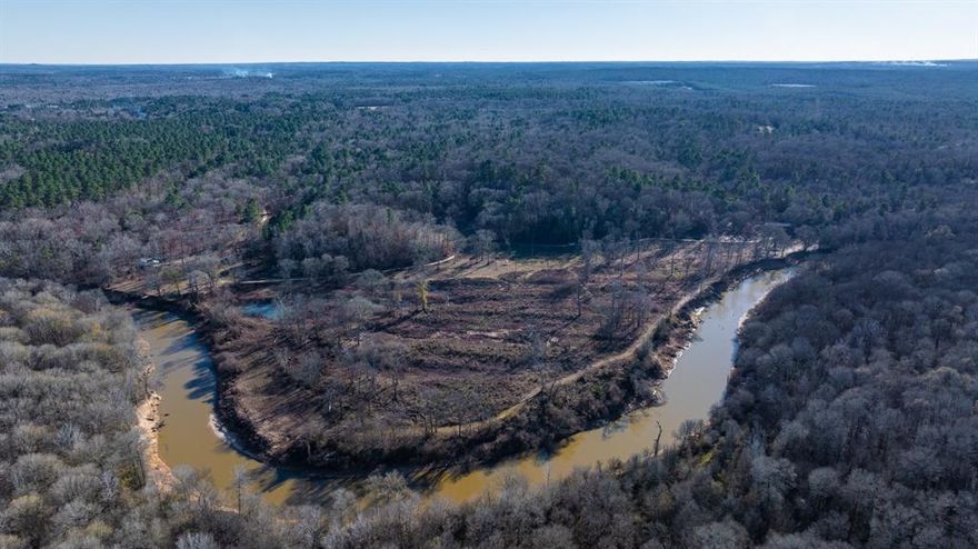 River Ranch—The Quintessential East Texas Recreational Ranch for sale. With 435 acres of land located near Gladewater, Texas, in Smith County—just two hours east of Dallas—River Ranch offers a premier recreational retreat in the heart of East Texas. This exceptional property showcases rolling topography, live-water creeks, open pastures, hardwood forests, and scenic pine ridges. With direct frontage on the Sabine River, it provides the perfect escape for those seeking outdoor adventure, relaxation, and investment potential.

The ranch features over five miles of trails, which are wide enough to accommodate four-wheel-drive vehicles easily. Multiple live-water creeks flow throughout the property, enhancing its beauty and ecological diversity. A highly improved 20-acre pasture offers prime grazing opportunities, while the sandy loam soil supports thriving hardwood bottoms and abundant wildlife habitat.

With 1.5 miles of road frontage, River Ranch offers excellent access and future development opportunities. Two older cabins sit atop a bluff overlooking the Sabine River, each equipped with its own water well and electric meter. The property includes approximately 0.5 miles of Sabine River frontage along a high bank, ensuring minimal floodplain impact. Established wildlife food plots create a turnkey hunting experience for Whitetail deer and wild hogs.

The ranch is home to a diverse mix of native tree species, including White Oak, Red Oak, Water Oak, Hickory, Ash, Loblolly Pine, Beech, Dogwood, and River Birch. Whether you enjoy riding trails on horseback, birdwatching under the towering hardwoods, fishing for catfish along the Sabine River, or hunting in the river bottom, River Ranch offers something for everyone.

This unique property blends natural beauty, recreation, and investment potential in one incredible East Texas location. Invest in Texas - Buy Land!
