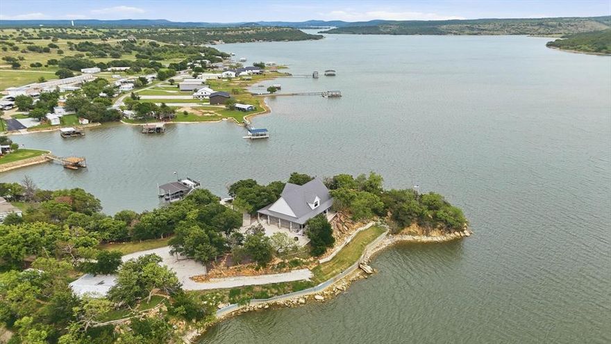 Set on the peaceful west side of PK,  this property sits on 1.5 acres of secluded  waterfront providing outstanding privacy, calm DEEP waters and expansive open lake views.  The property is thoughtfully arranged to highlight outdoor living with tiered terraces, shaded gathering areas and stone pathways that lead naturally to the waters edge, a multilevel private dock serves as the centerpiece of lake life.  The dock features 2 boat slips, 1 personal watercraft slips & generous covered, open areas designed for relaxing or entertaining family & friends,  Completed in 2022, the custom built home offer a modern open layout that connects seamlessly to the outdoors.  The main living area features soaring ceilings, expansive windows framing the lake, statement lighting and a centrally located wood-burning stove.  The chef's kitchen is designed for gathering after long days on the water & includes premium stainless steel appliances double refrigerator & ovens, abundant cabinetry & ample storage.  The main level includes a spacious primary suite with a soaking tub, walk-in shower & separate closets, along with a guest bedroom full bath & utility room.  Upstairs, a loft overlooks the living area accompanied by 2 additional bedrooms, a full bath and generous storage.  An unfinished attic space offers flexibility for future expansion.  This private peninsula property delivers a rare opportunity to enjoy P K Lake at its finest- combining privacy, modern luxury, protected waterfront & spaces designed for true lake living.
