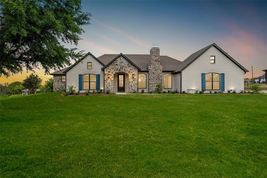 Discover this stunning new construction home situated on a full acre, ideally located just 25 minutes from Fort Worth and 10 minutes from the tollway—offering the perfect blend of privacy and convenience. Opportunities like this are rare in the rapidly growing area of Benbrook. This thoughtfully designed home features 3 bedrooms, a dedicated office, and 2.5 bathrooms. Engineered hardwood flooring flows throughout the main living areas and the spacious primary suite. The home is enhanced with custom cabinetry and detailed inlay work, adding both elegance and functionality. The laundry room includes a utility sink and ample storage.The exterior showcases a charming Cotswold cottage-inspired design with a cobblestone-accented facade, white-painted brick, striking black windows, and classic shutters. Inside, quartz countertops throughout tie together the home’s elevated finishes. This is a rare opportunity to own a custom-style home with acreage in a prime location.