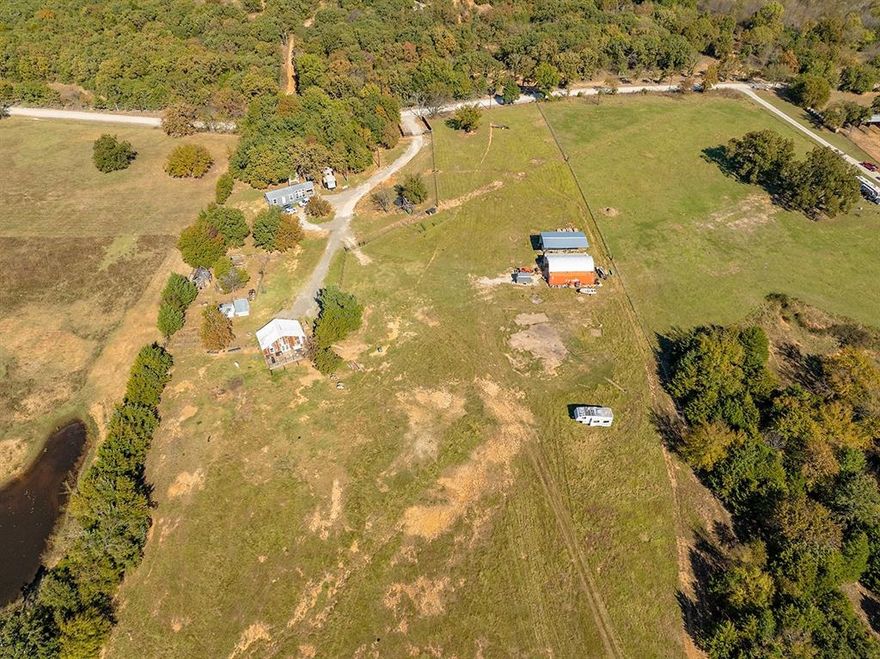 Use of Preferred Lender will offer to pay .75 points of buyer’s closing costs. Call TODAY to see if you Qualify! Unique Rustic Barndominium on Over 10 Acres! Discover the perfect blend of rustic charm and modern living in this stunning 2-bedroom, 1-bathroom situated on over 10 acres of breathtaking countryside. This property offers expansive views and ample space for relaxation, recreation, and work, making it a rare find. The spacious living areas feature exposed rafters that enhance the open feel, complemented by wide plank wood floors that add warmth and character. The gourmet kitchen boasts an open concept design that seamlessly flows into the living area, featuring butcher block countertops, a beautiful travertine backsplash, and a farmhouse sink with stunning views of the land. It comes equipped with stainless steel appliances and bar seating for casual dining. The master suite is thoughtfully located at the back of the home for added privacy and includes a private entrance into the rustic glam bathroom with double sinks on a repurposed dresser, elegant gold accent mirrors, and a tiled shower and tub area. The second bedroom is designed with a custom closet system, offering versatile storage options. Outdoor living is equally impressive with an expansive back deck, perfect for hosting gatherings or enjoying tranquil sunsets. Beneath the house, there’s an open stable area ideal for animals or extra storage. The property is fully fenced and cross-fenced, featuring an RV hookup complete with water, sewage, and electricity, along with a built patio for convenience. Additionally, a designated garden area includes a greenhouse and a fenced space ready for your gardening projects.Don’t miss this incredible opportunity to own a piece of paradise! Whether you’re looking for a serene retreat or an active lifestyle, this Barndominium has it all.