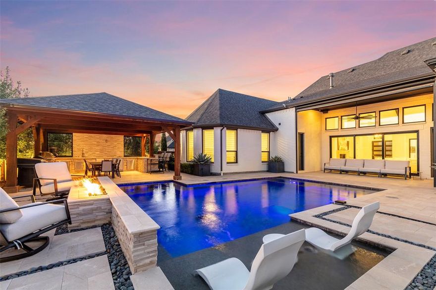 This SINGLE-STORY home in Mustang Lakes, one of Celina’s most sought-after master-planned communities, is designed for both serious entertaining and wine collection. The gated courtyard features outdoor speakers that set the tone for refined gatherings. At the heart of the home is a remarkable, custom walk-in, temperature-controlled wine room with up to 1000 bottle capacity. Enclosed in wrought iron with LED lighting, the space includes a tasting bar, an adjoining sitting area, and a custom-built service armoire, over $100K enhancement. Soaring vaulted ceiling and open-concept living spaces transition seamlessly to the outdoors through a dramatic folding glass wall that opens the living room to the backyard. An electric screen allows the patio to be fully enclosed when desired, creating year-round flexibility. An in-home media system extends throughout the residence, including all common areas and primary suite. Natural light floods the kitchen with a huge island, double ovens, pot filler, and a generous amount of ceiling height cabinetry and quartz counterspace. All bedrooms have ensuite baths. The backyard is designed to rival private resort settings, showcasing a custom-designed pool with hot tub, tanning bed, waterfall feature, programmable light show, and firepit. A stand-alone, covered outdoor Cabana kitchen provides extensive functionality with a grill, sink, refrigerator, storage, bar seating, and generous countertops, ideal for both intimate evenings and large-scale entertaining. An outdoor half bath with a dedicated pool storage closet adds thoughtful convenience. Beautiful landscaping completes the experience with seven RH Zinc planters, custom lighting, and irrigation, creating architectural symmetry and evening ambiance. Offering the ease of single-story living combined with architectural wine presentation and true indoor-outdoor integration, this Mustang Lakes residence delivers distinction, scale, and lifestyle in one extraordinary home.