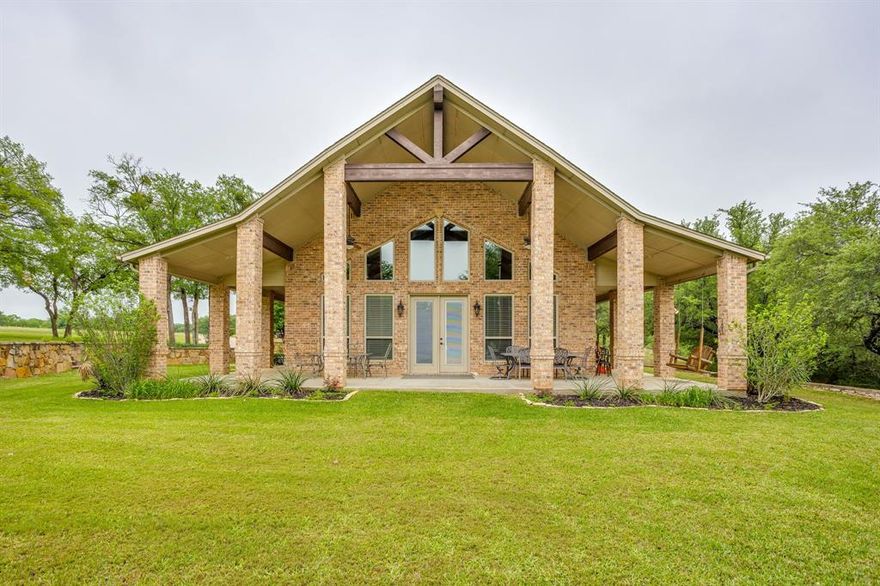 Set on a quiet, private stretch of waterfront on the Fort Worth side of Lake Granbury, this rare custom home offers the ideal balance of seclusion, accessibility, and a beautiful view of the lake. Positioned in a protected cove with a clear sightline to the main body of water, the property delivers both calm shoreline living and scenic water vistas. Built in 2012 by Couto Homes, this fully custom 4-bedroom, 3-bath home was thoughtfully designed with oversized walkways and doorways to provide ease of movement and wheelchair accessibility throughout. The open-concept floor plan is anchored by expansive floor-to-ceiling windows that frame the lake, filling the home with natural light and uninterrupted views. The main living area features a gas fireplace and flows seamlessly into the kitchen and dining spaces, creating an ideal setup for both everyday living and entertaining. The primary suite is located on the main level and includes a private exterior door leading directly to the wraparound porch, perfect for quiet mornings or evening lake views. Outdoor living is a standout feature, with a wraparound porch spanning three sides of the home (excluding the garage side), offering multiple vantage points to enjoy the water and surrounding landscape. The 1.29-acre property consists of three parcels, with the main parcel currently benefiting from an agricultural exemption.
Additional highlights include: Private well water; Lake-fed sump pump for the sprinkler system; Covered dock with space for a boat and jet skis; Extensive stone retaining walls that terrace beautifully down to the water’s edge.
Located within a small, low-impact HOA community, this property offers a rare opportunity to own a private, well-built waterfront home with both functionality and timeless design. Schedule your private showing today to experience this exceptional lakefront property in person!