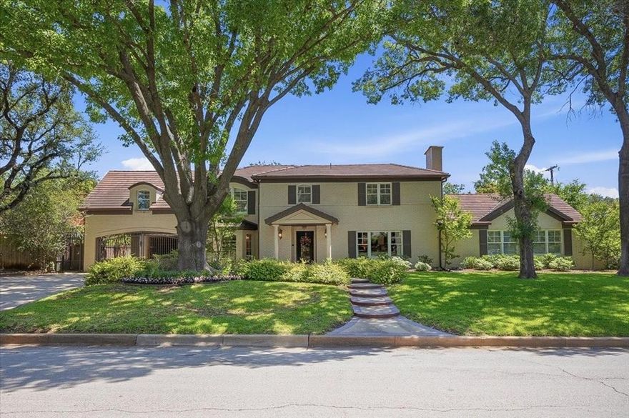 Set in one of Fort Worth’s most desirable pockets, just moments from River Crest Country Club and the Camp Bowie bricks, this home pairs an exceptional location with a thoughtfully maintained, timeless design. Offering 5 bedrooms and 5.1 baths, the layout is both generous and flexible, with two primary suites—one on the main level and a second upstairs—creating options for a variety of living arrangements. A spacious office and dedicated wine room add to the home’s functionality, while multiple living areas provide a comfortable flow for both everyday use and entertaining.
The kitchen is well-equipped with stainless appliances, ample workspace, and a functional island, opening easily to the main living areas. Natural light fills the home, enhanced by updated windows, wood flooring, and custom built-ins that bring warmth and character throughout.
The main-level primary suite features an updated bath and a custom closet, while upstairs includes three additional en suite bedrooms, the second primary suite, and a flexible bonus space suited for a secondary office, playroom, or lounge. Outdoors, a covered living area with travertine flooring, vaulted ceilings, a stone fireplace, and a built-in grill extends the living space and creates an inviting setting for gathering or unwinding. A great opportunity to own a well-positioned home with scale, flexibility, and lasting appeal in a premier location.