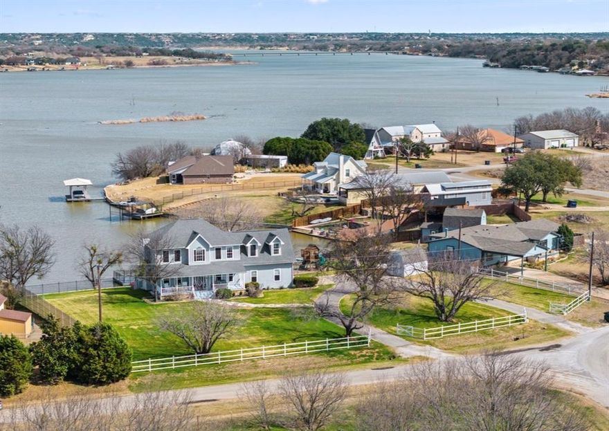 Lakefront living at its finest in Granbury on the shores of Lake Granbury! This spacious 6-bedroom, 2 full bath home offers incredible flexibility, scenic water views, and direct access to the lake with a private dock. Inside, you’ll find an inviting layout filled with natural light and beautiful lake views from the main living areas upstairs and downstairs. The kitchen features granite countertops, ample cabinetry, and generous prep space, flowing seamlessly into the dining and living areas ideal for entertaining. The basement level provides additional living space and privacy, making it perfect for guests, extended family, or a second primary-style retreat. Outdoor living truly shines here. Enjoy peaceful mornings and sunset evenings from the upstairs patio deck overlooking the water. The backyard is designed for relaxation and recreation, featuring a new built in fire pit area for friends and family gatherings, new playground space for the kids, and a new built-in outdoor rack for convenient storage of swim gear and lake essentials. The private dock offers easy access to boating, jet skis, fishing, and endless days on the water. This home has been thoughtfully enhanced with numerous recent upgrades that elevate both curb appeal and everyday comfort. Enjoy all-new professional landscaping, a newly constructed retaining wall with iron fencing and integrated lighting. The exterior has been freshly painted, creating a clean, updated look. Additional improvements include a new AC unit, new fencing in both the front and backyard, and a full sprinkler system servicing both yards for easy maintenance. The circular driveway enhances curb appeal while with plenty of room for boats, RVs, and multiple vehicles. Whether you’re searching for a forever home, an Airbnb, or a weekend getaway where peace and lake views greet you daily, this property offers the space, setting, and lifestyle to truly experience the best of waterfront living.