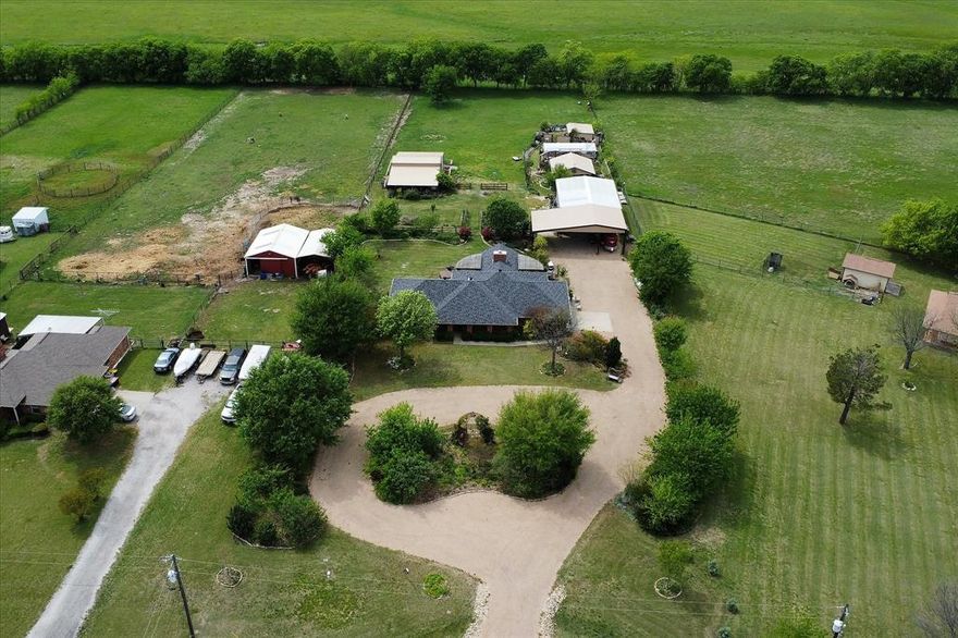 Welcome to a truly one-of-a-kind property where breathtaking views, thoughtful upgrades, and country charm come together in perfect harmony. Nestled on nearly 2 acres of rolling hills, this stunning mini-farm offers wide-open skies, unforgettable sunsets, and peaceful surroundings where neighbors are spaced out and the stars shine bright at night. Inside, you’ll find a beautifully updated home featuring a split floor plan and an open-concept living space designed for both comfort and entertaining. The kitchen has been completely remodeled, showcasing modern finishes and functionality that flows seamlessly into the main living areas. This property is as versatile as it is beautiful. A converted garage creates a private suite—ideal for a mother-in-law space, guest quarters, or even a home-based business. For those who need room to work or create, the insulated shop and multiple outbuildings provide endless opportunities, including space for a home business or hobbyist’s dream setup. Equestrian and agricultural enthusiasts will fall in love with the fully cross-fenced land, complete with a six-stall barn, ample trailer parking, and a massive four-car covered parking area. Whether you have horses, cattle, or FFA projects like pigs and goats, this property is ready to support your lifestyle. The grounds are nothing short of magical. Designed by a horticulturist, the landscape is filled with thriving native perennials that return year after year, creating a vibrant, ever-changing display. The yard is a certified haven for monarch butterflies, pollinators, and a wide variety of birds, offering a peaceful, garden-like setting that feels like your own private botanical retreat. Outdoor living is elevated to another level with a beautifully designed living space. Located just minutes from the lake, this property offers the perfect blend of rural tranquility and convenient access to recreation. This is more than a home—it’s a lifestyle.