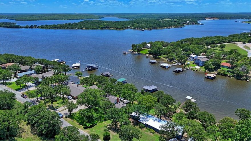 LAKE HOME – Welcome to this spacious 2 story, 5 bedroom, 3.5 bath, 2 car garage, brick home. It offers a large kitchen with adjoining dining area, expansive living area includes with a fireplace and big windows allowing wonderful views of the lake. Outside is a large concrete patio with a wonderful tree shaded yard with sprinkler system. The private covered dock with a boat slip and 2 watercraft docks. The property is located just a cart ride away from the The Top of Lake Golf Club.