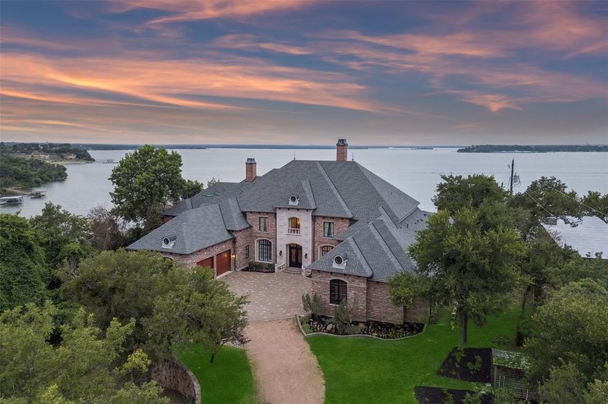 Experience the pinnacle of lakeside luxury in this extraordinary custom home nestled on the shores of Eagle Mountain Lake. Thoughtfully designed for both elegant entertaining & everyday comfort, this expansive residence boasts 5 bdrms, 6 full baths, 2 half baths & an unmatched blend of modern amenities. From the moment you step through the grand entrance, panoramic lake views captivate your attention through the family room’s expansive windows. To one side, a formal dining space sets the tone for special occasions, while to the other, the secluded primary suite serves as a private sanctuary. This lavish retreat features a cozy sitting area w-a see-through FP, dual spa-inspired bathrooms, heated floors, a wet bar, 2 large WIC's + a connected fitness room. A steam shower, safe room & private laundry area complete the suite’s luxurious amenities. Gourmet kitchen is a culinary masterpiece, fully equipped w-top-of-the-line Viking Apps including a 6-burner gas cooktop, double ovens, full-size BI wine fridge, two dishwashers + a spacious island w-a trough sink & foot-pedal-controlled faucet. Lighted cabinetry, pantry & a BI fridge elevate both style & function. A secondary suite w-its own kitchen + full bath provides ideal accommodations for guests. Upstairs, 3 additional bedrooms accompany a large game rm, media rm + private office—each offering access to balconies overlooking the lake. Step outside & relax in the infinity-edge pool, cook up a feast in the outdoor kitchen, unwind by the fire pit, or rinse off in the outdoor shower. The covered patio is enhanced w-retractable shades for all-season comfort & a boat dock trolley offers easy lake access. There’s even a dedicated dog run. Smart home is loaded with high-end features including Control4 automation, foam insulation, water filtration system + abundant storage. Car enthusiasts will appreciate the three 2-car garages—including one located beneath the main garage w-internal access. Enjoy unrivaled lakeside lifestyle.