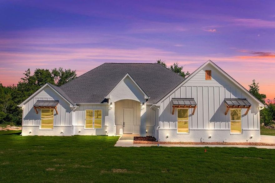 Step into this stunning modern farmhouse featuring an all-white exterior and timeless curb appeal. The heart of the home is a gorgeous kitchen with a striking green island, complemented by champagne bronze finishes — perfect for cooking, entertaining, or gathering with loved ones. Relax in the living area with a beautiful floor-to-ceiling fireplace that adds warmth and elegance to the space. Step outside to a spacious backyard featuring a covered patio, ideal for outdoor dining, entertaining, or simply enjoying your surroundings. This home seamlessly blends modern luxury with farmhouse charm, offering both style and comfort for everyday living and entertaining.