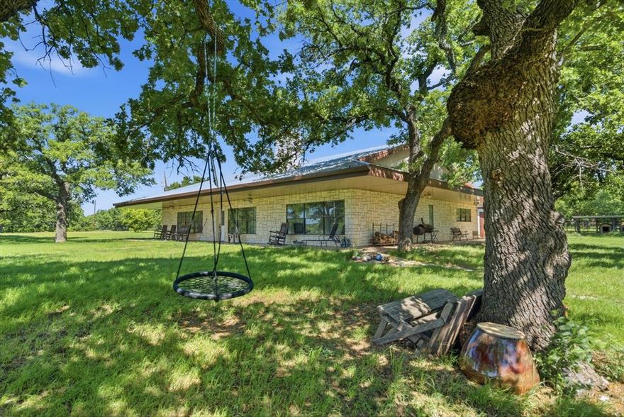 Incredible high-fenced ranch property located just south of Cisco, offering a beautiful blend of diverse terrain and natural features. The land showcases impressive elevation changes, ranging from fertile bottomland to rolling hills, highlighted by a striking rock outcropping that adds character and scenic appeal. A picturesque wet weather creek area is lined with mature trees, including oak, mesquite, and pecan, providing both shade and wildlife habitat. Water on the ranch is provided by a water well that supplies the house and also 6 stock tanks for livestock, wildlife and fishing.
The property consists of approximately 200 acres of wooded land and an additional 60 acres of pasture, featuring a mix of native grasses and coastal Bermuda—ideal for grazing or recreational use.
The charming stone home offers 3 bedrooms and 2 bathrooms, along with a spacious kitchen and comfortable living areas, perfect for relaxing or entertaining.  There is also a separate building that has a large open area that would be great for a game room, trophy room, workout room or anything you can imagine! This building has its own bathroom, a loft and also houses a 24x36 two car garage or workshop.  There is yet another building that is a 60x30 three car garage.  Equipped for livestock or equestrian use, the property includes two barns—one measuring 50x18 and the other 36x36. One barn is outfitted with two 12x15 horse stalls, and a round pen is already in place, making this an excellent setup for horse enthusiasts. Conveniently located just 50 minutes east of Abilene and approximately 1.5 hours west of Fort Worth, this ranch combines peaceful country living with easy access to nearby cities.