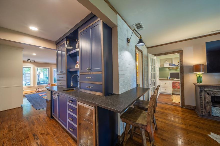 This beautifully renovated 1940 West Kessler home honors its architectural heritage while embracing contemporary sophistication with over 3,100 square feet of designer-curated space, where every detail was chosen with intention. Positioned on one of Oak Cliff’s coveted, quiet, one-way streets, up from the 3rd hole on Stevens Park Golf Course and under 1.5 miles to Bishop Arts District. The main level features a primary sanctuary with spa-inspired ensuite, including a soaking tub within a walk-in shower, custom closet, private patio access, and elegant herringbone floors. At the heart of the home, an entertainer’s hub showcases a wraparound wet bar with dual wine refrigerators connecting three distinct living areas. The kitchen offers professional stainless appliances, leathered granite countertops, a prep island, a sizeable walk-in pantry, and screen porch access. The formal dining room preserves original arched doorways and sits adjacent to both the custom bar and chef’s kitchen. A converted side porch with generous built-in storage serves as a dual home office, while an additional first-floor ensuite bedroom provides flexibility for guest or multi-generational living. Upstairs, a split-bedroom layout centers around a spacious family room. Two bedrooms with custom closets share a designer full bath with double vanities with a stunning tiled shower. A 100 sq ft bonus space with dormer windows offers the perfect reading nook, meditation room, or whimsical children’s hideaway. Outdoor living includes a screened entertainment patio flowing to an elevated dining deck and a custom soaking pool with full filtration and composite decking. Mature landscaping creates beautiful, functional zones for dining, lounging and play. A substantial 2021 addition seamlessly blends old and new. Designer details include curated wallpaper and crown molding throughout. Major system updates include HVAC, roof, and plumbing. An oversized laundry room with utility sink adds convenience.