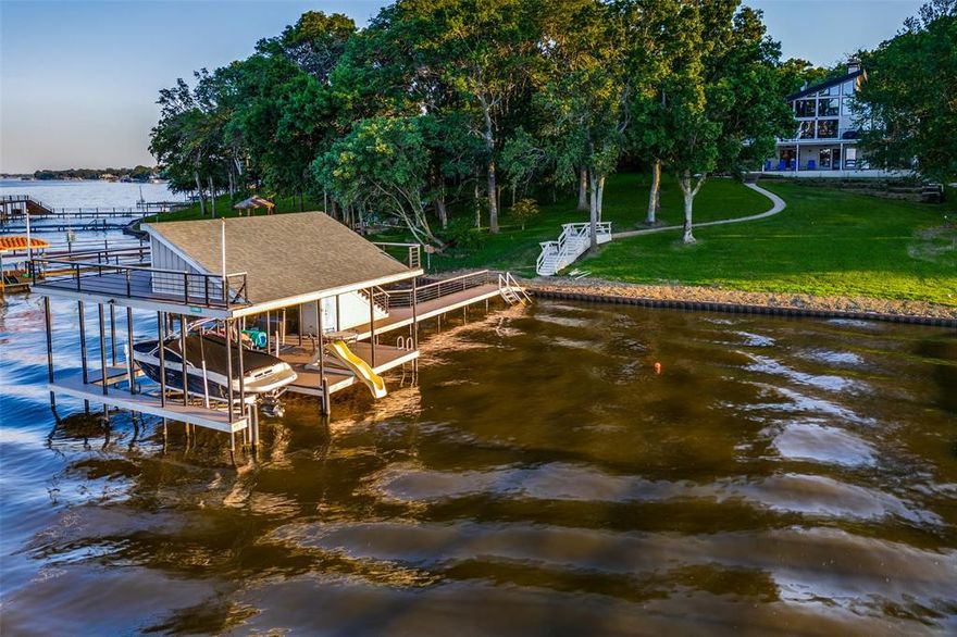 Find the very best of Cedar Creek Lake in the gated Heather Woods neighborhood on the west side of the lake. Designer kitchen features an oversized island, KitchenAid induction five burner cooktop and double oven, and built-in KitchenAid refrigerator (ice maker and two drawer fridge). Gorgeous views of open water, protected from south wind & western sun exposure + 10-12 feet of water at the boathouse. This generous space allows flexibility for entertaining and hosting a large group or multiple families. The sq ft is efficiently distributed across two levels. 2021 construction TREX composite boathouse with custom-cradle lift for large ski boat, personal watercraft lift, and party deck with steel pipe supports and railing. Whole house water filtration system helps ensure clean drinking water and protects ice makers.  This house has exceptional storage space as well, which is not the case in some lake houses. New corrugated steel retaining wall with concrete bulkhead (2024), new sidewalk leading from boathouse, and new backyard elevated deck (2024).