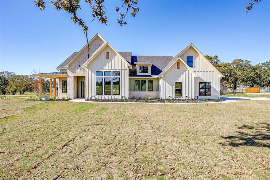 This home sets a new standard for what you desire in your new construction home, with no detail overlooked as the builder originally planned to move in himself. You will appreciate the layout, finish-out and pride in construction shown in this home!  The side porch and cedar posts are a unique touch to the exterior. Inside you will discover 14' ceilings, abundant natural light, beams in ceiling and elevated design choices. The elaborate kitchen includes a custom range hood, cooktop, double ovens, and microwave built into the 8' island, a beverage cooler and bar area, an oversize window with farmhouse sink, floating shelves and designer lighting. The upstairs bonus room can be used as a bedroom with a full bathroom and closet included.  The master bathroom includes his and her vanities, massive closet, freestanding tub and frameless shower glass door.  This property offers a sense of escape, while being only 4 miles to the highway. Agent related to builder with ownership in property.