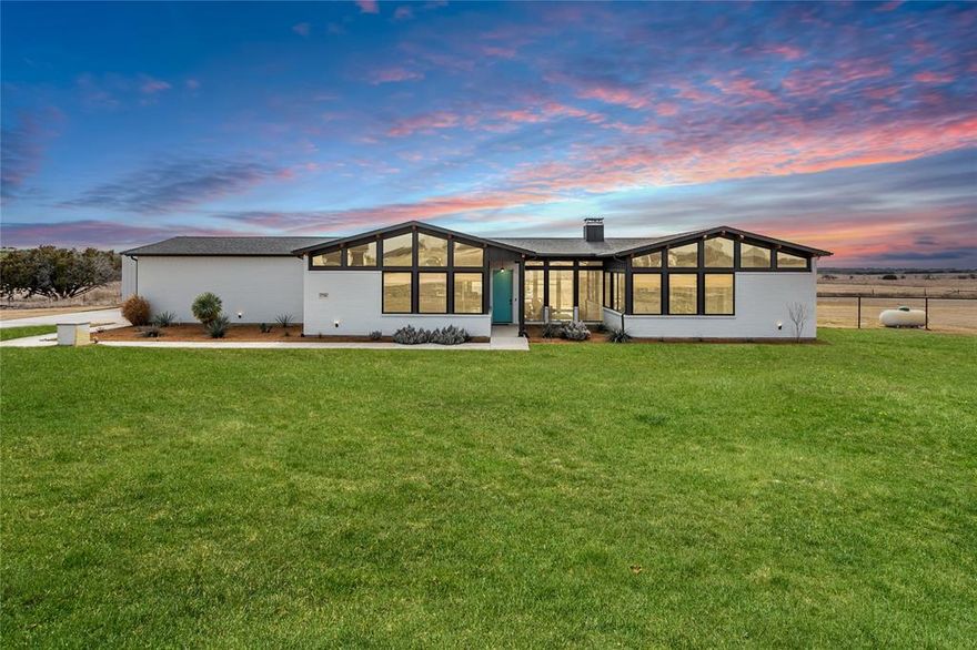 This custom-built mid-century modern home sits on a private 2-acre setting and blends timeless design with thoughtful luxury. Expansive windows throughout flood the home with natural light and frame stunning views of the open plateau, with no neighbors behind for added privacy. The heart of the home features an impressive chef’s gas range, ideal for both everyday living and entertaining. A striking double-sided gas fireplace connects living spaces and adds warmth and architectural interest.

The home offers four spacious bedrooms and three full bathrooms, including a luxurious primary suite with a large soaking tub, separate shower, and beautifully executed custom tile work. Exposed beams span the ceilings, enhancing the mid-century character, while custom lighting and top-of-the-line closet systems add both style and function.

Outdoor living is just as inviting with a covered back porch overlooking a massive backyard, perfect for relaxing or hosting gatherings. The property includes an attached three-car garage plus an additional approximately 1,200-square-foot workshop with space for up to six vehicles, ideal for car enthusiasts, hobbies, or extra storage.

A rare combination of architectural design, space, and privacy, this home offers a unique lifestyle opportunity on acreage with unforgettable views.