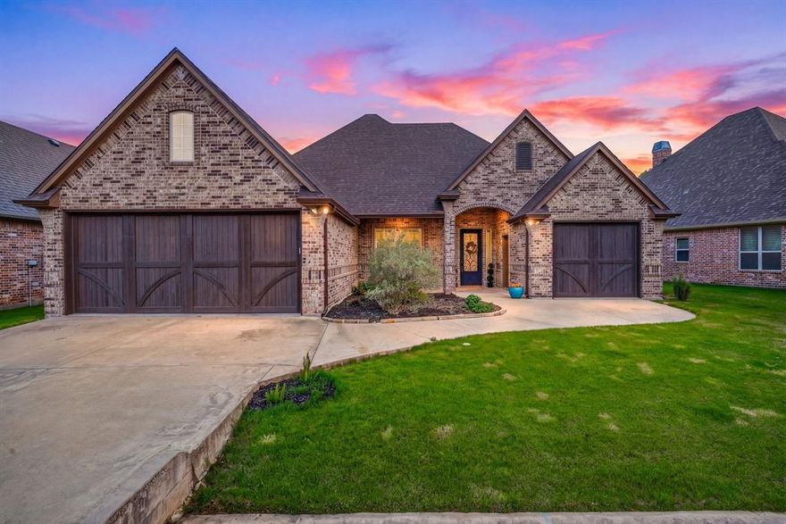 Enjoy living in the gated community of Pecan Plantation, with peaceful fairway views in both the front & backyards. Refined living in this beautifully designed 3-bedroom, 2-bath home with a dedicated office, perfectly positioned on the Nutcracker Golf Course. From the moment you arrive, the stunning iron front door sets the tone for the quality and character found throughout. Inside, rich wood flooring flows through the main living areas, complemented by crown molding, custom cabinetry, & a warm, inviting color palette. The open-concept layout is ideal for both everyday living & entertaining. The kitchen overlooks the living room and golf course beyond. The kitchen is a standout feature, offering granite countertops stainless steel appliances, gas cooktop, double ovens, microwave, refrigerator, pantry, and an oversized island perfect for gathering. A beautifully vent hood, designer backsplash & pendant lighting add a custom touch, while the living area is anchored by a cozy electric fireplace & filled with natural light.  The spacious primary suite provides a private retreat with a large ensuite bath featuring dual sinks, a soaking tub, a walk-in shower, and generous storage. Secondary bedrooms and a dedicated office offer flexibility for guests, hobbies, or working from home. Step outside to the enclosed back porch ideal for year-round enjoyment—overlooking the golf course, along with a low-maintenance yard. You can irrigate your lawn from the Pecan Orchard for a minimum of 15.00 month. Additional highlights include a 2-car garage plus golf cart garage and walk-up attic access for convenient storage.  Many amenities to enjoy including two golf courses, clubhouse, 2-pools, parks with Brazos River access, walking trails, playground, dog park, sports fields, grocery store, dining, medical clinic, veterinarian, Ace Hardware, car wash, gas station, lake access with a marina, RV park, archery, community garden, 2 air strips, hotel at clubhouse, tennis & even pickle ball!