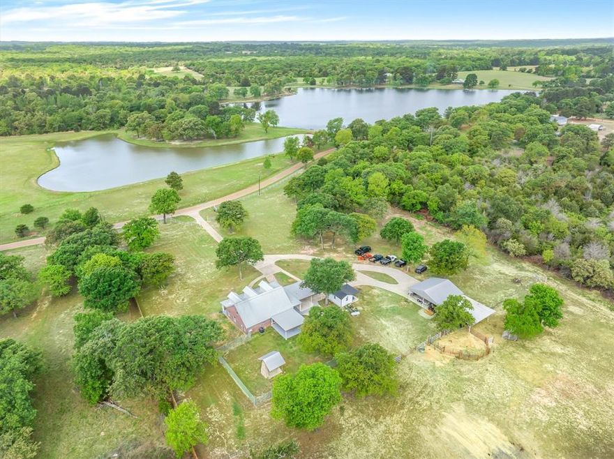 Nestled on 12.5 acres of rolling East Texas countryside, this beautifully maintained residence blends modern comfort with peaceful rural living. The open-concept main living area features abundant natural light and a thoughtfully designed kitchen, stainless appliances, and an oversized island—ideal for everyday living and entertaining. The primary bedroom is downstairs, while all other bedrooms are upstairs with additional bedrooms and flexible living areas accommodate guests, a home office, or a hobby room. Outside, manicured yards, mature trees and pastureland provide year-round privacy and scenic views. Fenced areas and a convenient equipment barn or covered workspace support small-scale agricultural use, equestrian hobbies, or recreational vehicles. Located minutes from local amenities yet far from the bustle, this property offers the rare combination of accessibility and secluded country living in desirable East Texas.