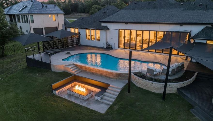 Experience elevated living inside one of Flower Mound’s most exclusive gated and secured communities. This extraordinary estate delivers a rare combination of luxury, functionality, and comfort with an assumable 3.1 percent loan that makes owning it as smart as it is spectacular. From the moment you walk through the doors, there is an immediate sense of calm and openness. The layout flows effortlessly beneath 14-foot ceilings with natural light pouring through a wall of windows. The kitchen is the heart of the home, a chef’s dream with a massive island that makes cooking and entertaining easy, whether it is Sunday breakfast or a full house of guests. A 30-foot panoramic glass door opens completely, connecting the living room to the backyard in a way that makes the space feel alive. Step outside and you will see why this home was designed for both living and leisure, featuring a sparkling pool, outdoor kitchen, granite firepit seating, and shade sails that create a private resort feel. Every inch of this home was designed for comfort, with two washers and dryers in the utility room, a whole home Sonos sound system, and dual Nest thermostats to keep each area just right. The primary suite is private and serene, with a flex room perfect for an office, nursery, or gym, and a custom closet that connects directly to the laundry room. Beyond the main home is a 6,500 square foot unfinished sports complex with HVAC, two bathrooms, and the framework for a golf simulator and pickleball court or anything your imagination can come up with. The seven-car garage includes a tornado shelter, and the detached guest house features two bedrooms, two bathrooms, a full kitchen, living space, and office for family or long term guests. Set within a gated enclave bordered by the rolling greens of Tour 18, this home offers privacy, convenience, and elegance with an unbeatable 3.1 percent assumable loan.