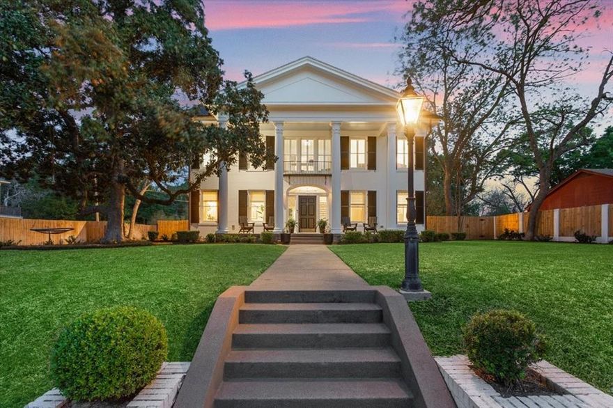 Luxury, timeless design, and Greek Revival elegance converge at this extraordinary Cameron Park estate. Located at 410 Rice Avenue in the heart of historic Cameron Park, this one-of-a-kind residence offers 5,043 square feet in the three-story main home, complemented by a beautifully appointed guest house—ideal for refined living and entertaining. From the moment you arrive, the home makes a lasting impression. A grand front porch framed by four massive Greek columns, Bevolo gas lanterns, and cedar shutters with iron hinges sets the tone. Inside, an elegant entry hall features a sweeping staircase with paneled wainscoting and dentil molding, alongside a hand-painted mural by artist Sean Oswald capturing the spirit of Cameron Park and Waco. The first floor balances entertaining and everyday living. A formal dining room with an 18th-century Empire-style chandelier flows into a sophisticated living room with a 19th-century Italian chandelier and hand-carved stone mantel. A sunroom with a box-beam ceiling offers serene views, while a richly detailed study includes walnut-inlaid walls, French doors, and a stone patio. At the heart of the home, the kitchen features a marble island, Sub-Zero paneled refrigeration, a La Cornue range with polished brass, and a well-appointed pantry. A fireplace with Dutch Delft tiles and an adjacent wet bar complete the space. Upstairs, the primary suite offers marble finishes, custom tilework, and a spacious dressing room. With 5 bedrooms and 5.5 baths, the home comfortably accommodates family and guests. Modern amenities, including Sonos speakers, blend seamlessly with historic character. Remodeled in 2018 with reverence for its past, this residence combines history with modern comfort. Just moments from Cameron Park, the Brazos River, downtown Waco, and Baylor University, this is more than a home—it’s a rare piece of Waco’s architectural legacy.
