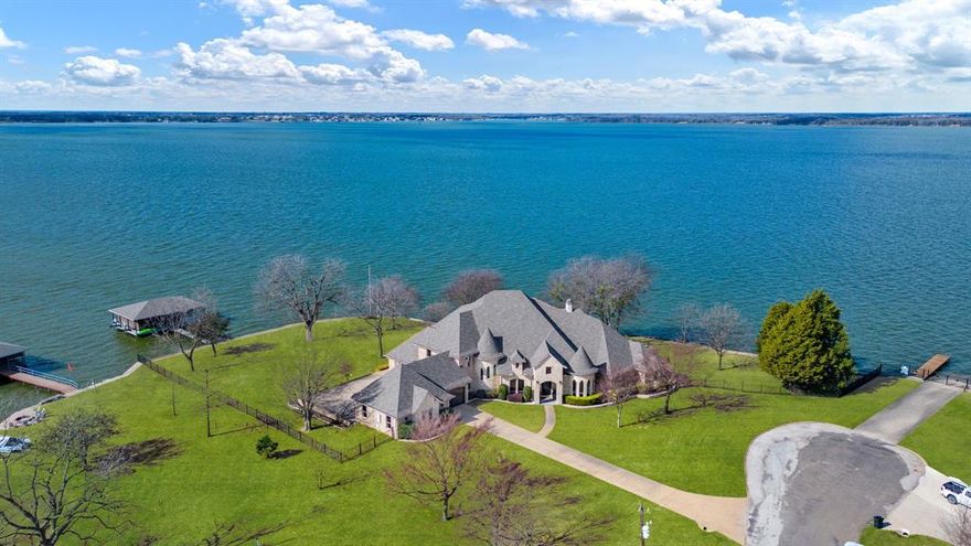 Welcome to this gorgeous two-story lake house, a true sanctuary for those who cherish waterfront living. Spanning over an acre with an impressive 426 feet of lakefront property, this home features 5 spacious bedrooms and 6 bathrooms, offering ample space for family and guests. The heart of the home is the expansive kitchen, complete with two islands and plenty of counter space. Enjoy high-end Thermador and KitchenAid appliances, as well as convenient roll-out shelves in the cabinets. The adjoining dining room and breakfast nook provide perfect settings for meals and entertaining. The inviting living room boasts built-ins, a cozy fireplace with gas logs and an electric starter, creating a warm ambiance. An office with built-ins offers a quiet space for work, while the stylish bar features a wine refrigerator and built-in wine shelving—ideal for hosting gatherings. The media room is a highlight, equipped with a projector, surround sound, built-ins, a sink, and a wine refrigerator, ensuring an exceptional movie experience. Retreat to the primary bedroom, complete with a sitting area, fireplace, en-suite bath with custom closet, a separate shower equipped with two shower heads, along with a private door leading to the back porch with stunning lake views. A second primary suite on the main level also features an en-suite bath and fireplace. The outdoor living space is just as impressive, featuring a back porch with an outdoor kitchen and spiral staircase leading to a balcony. Upstairs, enjoy a game room (with a pool table that stays), built-ins, a sink, wine refrigerator, and a door leading to a balcony. Three additional bedrooms upstairs provide comfort and privacy, including one with a large walk-in closet and balcony access. The dock features two boat lifts, two jet ski lifts, a sink, refrigerator, and a retractable boat cover. With three walk-in attics for additional storage, this lake house is the ultimate retreat for relaxation and recreation.