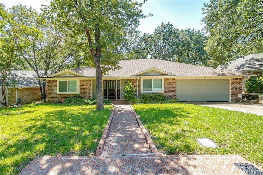 Welcome to 5704 Firewood Drive, Arlington, TX 76016 — a beautifully updated 3-bedroom, 2-bath home offering 1,979 square feet of thoughtfully designed living space in an established, tree-lined neighborhood.
From the moment you arrive, mature trees and a classic brick exterior create inviting curb appeal. Inside, the home opens to a spacious living area highlighted by vaulted ceilings with exposed beams, updated flooring, and a striking painted brick fireplace that anchors the room and creates a warm, welcoming focal point. The open layout flows seamlessly into the dining area, making it ideal for both everyday living and entertaining.
The updated kitchen features crisp white cabinetry, sleek quartz countertops, stainless steel appliances, modern fixtures, and a clean tile backsplash, offering both style and functionality. Just beyond, a dedicated dining space is filled with natural light and accented by updated lighting.
The primary suite provides a comfortable retreat with ample space, plush carpet, and an en-suite bathroom showcasing modern finishes, updated tile, separate shower and a soaking tub. Secondary bedrooms are generously sized and versatile, including a dining room currently styled as a nursery with updated flooring and designer lighting. Both bathrooms reflect thoughtful updates with clean, contemporary touches throughout.
Step outside to enjoy a large backyard shaded by mature trees, offering plenty of room for outdoor play, entertaining, or relaxing under the Texas sky. The covered patio provides a perfect spot for morning coffee or evening gatherings.
With updates throughout the home, spacious living areas, and a convenient Arlington location close to parks, shopping, dining, and major highways, this home offers comfort, style, and practicality all in one.