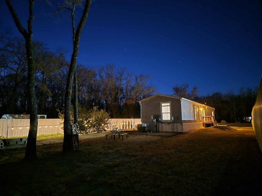 Nearly half an acre, built in 2022, near Cedar Creek Lake and move-in ready! Without the HOA or city-limit restrictions! In like-new condition, this 2 bedroom, 2 bathroom manufactured home offers approximately 1,088 square feet of efficient, well-designed living space on a recently surveyed 0.461 acre lot. The interior features an open living and kitchen layout with modern cabinetry, neutral finishes, recessed lighting, and durable flooring throughout. The kitchen provides ample cabinet storage, pantry space and counter space, and the refrigerator, washer, and dryer will convey with the property. Both bedrooms are comfortably proportioned, and the primary suite includes a private bath with dual sinks, separate shower, and soaking tub. Outside, the property offers a long gravel drive, fenced yard areas, and mature trees providing privacy and shade. Utilities are already in place with city water, city sewer, and underground electricity connected. Additional power available for another residence, shop or RV spot! Located outside city limits with no HOA restrictions, this property offers flexibility while still being close to Cedar Creek Lake amenities and local conveniences. Minutes from the surrounding lake area & just an hour from the DFW metroplex. Clean, move-in ready option for buyers seeking low maintenance living on nearly half an acre.
