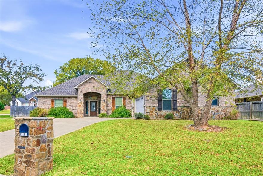 Beautiful single-story brick and stone home offering a functional layout with 3 bedrooms, a dedicated office (or 4th bedroom), and 2.5 baths has just become available for you to own. The open-concept design connects the living, dining, and kitchen areas, highlighted by hardwood flooring, crown molding, and a stone fireplace. The kitchen includes granite countertops, stainless steel appliances, a gas cooktop, a center island, a secondary serving island, tile backsplash, and generous cabinet storage. A separate office with built-ins provides workspace or study flexibility. The split layout places the primary suite on its own side of the home, featuring a large bedroom, dual-vanity bath, separate tub and shower, private water closet, and an oversized walk-in closet with built-ins. Two additional bedrooms share a full bath, and a half bath serves the main living spaces. Exterior features include a covered front entry, covered back patio, fully fenced backyard, mature trees, and a detached storage building with matching brick detail. A side-entry garage and extended driveway add convenience. Property includes a floor plan for additional clarity. Only a short drive to the South Tyler retail and dining corridor, offering access to shopping, restaurants, and essential services.