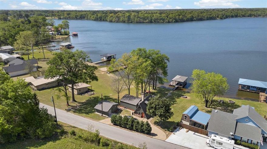Experience the laid-back charm of this rustic A-frame lakefront retreat, designed for relaxing weekends and outdoor fun. Vaulted tongue-and-groove pine walls and ceilings, rich hardwood floors, and an open living area create a cozy space to unwind after a day on the water. Floor-to-ceiling windows showcase beautiful lake views and fill the home with natural light, keeping you connected to the outdoors. A comfortable bedroom and loft offer inviting spaces to recharge. A flagstone path leads to a private dock with an electric boat lift—perfect for boating, fishing, or sunset cruises. A detached garage features an unfinished bonus room with a deck overlooking the lake, ideal for guests, a game room, or hobby space, with potential for a future bathroom addition. The property includes a certified, service-maintained aerobic septic drip system for easy ownership. Offered furnished and ready for immediate enjoyment, the retreat also includes a kayak, push mower, and riding mower—everything you need to jump right into lake living. Whether you’re seeking adventure or quiet relaxation, this A-frame is the perfect escape.