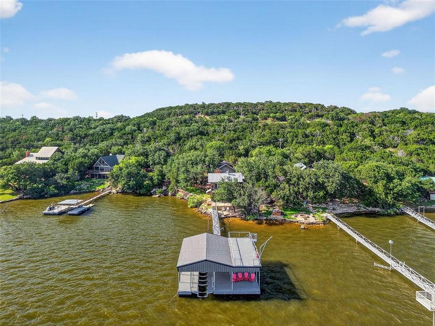 Best priced home with deep water dock on the lake!  Lakefront living has never been better in this remodeled home with NEW two story dock with boat lift that has decking underneath boat, jet ski house, and swing from upper deck.  This Peninsula residence sits on the RARE LOCATION of the coveted Colonels Row. This stunning property offers everything anyone could want in a lake property.  Enjoy the walk out water access just steps away from your patio. The open-concept kitchen promises a venue for hosting family or friends in comfortable luxury. Two living areas and two kitchens are ideal for entertaining your guests. The house has high ceilings, magnificent finishings and gorgeous hardwood floors in main living area. The grand owners suite features a fireplace, oversized standing shower, tub, plus incredible lake views. Enjoy endless amounts of outdoor entertaining on multiple outdoor patio spaces each with breathtaking water views. Guest house is perfect for an additional flex space for kids, games, or sleeping area. Storage shed.  Owner is agent.