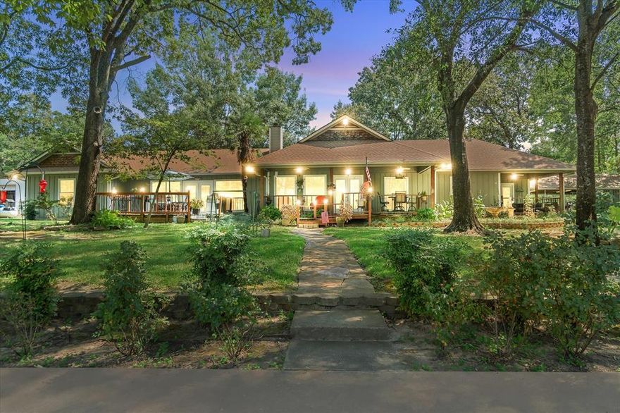 Meticulously maintained lakefront retreat on 2 acres is like none other with everything you need for enjoying lake life! Views are breathtaking at this Lake Holbrook home in nostalgic Mineola with a blend of charm, comfort and the best outdoor living. Nestled on 2 scenic acres at the end of a quiet cul-de-sac, this charming home is a private escape! Home features a private, split master floorplan with a private deck just off the master suite. Open concept kitchen, living, dining with 10 ft ceilings & stone gas FP and gorgeous large window views of the lake across the back. An additional 2nd living room space with 2nd stone gas FP and private deck that overlooks the lake just off the 2 guest bedrooms makes this a perfect VRBO, weekend getaway or your home daily retreat! Kitchen is large with breakfast bar, 2 ovens and plenty of cabinets and glass front cabinets. Outdoors the property has a showcase of beauty and function! The meticulously maintained front and backyard include mini gardens, all watered by sprinkler system on the outdoor well, several covered and uncovered outdoor seating areas, lush landscaping that complement the serene waterfront setting. A boathouse extends the lifestyle to the water set up with a fridge, grill and picnic tables that stay.  One of the storage buildings are set up for a fishing room and a dedicated man-cave add function to the fishermen lifestyle and gatherings.  Additional highlights are a 3-car detached carport, additional circle driveway 3 storage rooms total, separate areas for cooking out on grills. The side land parcel has open storage barns on the land for storage. Updates include, recent exterior paint, gutters, remodeled master bath with shower, Dual zoned HVAC and two HWHs.  Whether enjoying sunrise coffee by the water, hosting evenings in this amazing backyard, or casting a line off your own dock or boat, this property offers a lifestyle that is as comfortable as it is breathtaking.