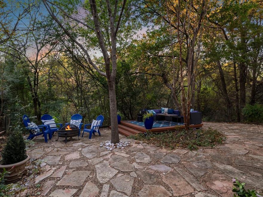 Absolutely you should open this Pandora jewel box of a home — a rare creekside retreat at the end of a quiet cul-de-sac where nature, privacy, and modern comfort come together. Backing to a wooded greenbelt that visually blends into McCree East Park, the backyard feels endless, offering a serene urban-nest experience rarely found in Lake Highlands and Richardson ISD.  Inside, sunlight pours through upgraded double-pane windows, highlighting the soaring two-story living room with warm oak paneling, a raised-hearth brick fireplace, and floor-to-ceiling glass framing the treetops. The dining area flows naturally from the living room, creating an inviting space for fireside meals and relaxed gatherings.  The kitchen overlooks the home’s stone-paved outdoor living areas and secret-garden atmosphere. Black granite countertops, fresh paint, under-cabinet lighting, a drop-down cookbook shelf, and the recently installed stainless refrigerator (which conveys) make the space both stylish and efficient. Sliding doors open to a dining deck and a second elevated platform set near the creek — ideal for morning coffee, yoga, sunset dinners, or quiet weekend moments surrounded by birdsong. Upstairs, the generous primary suite offers double closets, hand-painted sinks with a fresh floral motif, and a spacious shower finished in calming blue-and-white designer tile. A second ensuite bedroom adds flexibility for guests, work-from-home, or a dual-suite setup. This home delivers the rare mix of peaceful creekside living, low-maintenance outdoor spaces, modern updates, and intuitive indoor-outdoor flow. Minutes to White Rock Lake, Lake Highlands Town Center, the Arboretum, and major commuting routes, this is a truly special opportunity to live close to everything while feeling a world away. Of special note: Second lot that conveys runs along the right side of shared driveway. NO HOA community.