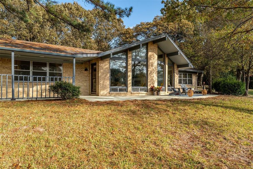 Discover a rare opportunity overlooking the shimmering waters of beautiful Lake Lydia in East Texas. Perched high on a hill, this rare fee-simple property located within the Lake Lydia Fishing Club community offers lake living at its best.  This mid-century modern gem exudes timeless sophistication, featuring clean lines, warm natural materials and walls of windows that frame boundless lake views. The main home has three bedrooms and two full baths with vaulted ceilings and an open floor plan. The updated kitchen looks out toward the wall of windows and the lake beyond. There is an enclosed patio large enough to have a dining area as well as create an artist haven. A guest house complete with kitchen, full bath and large bedroom compliment the main house and is ideal for visitors, multigenerational living, or rental potential. The property includes two additional outbuildings: a dedicated workshop with electricity and a concrete floor, plus a separate storage, shed or additional hobby space.  Sitting on just under an acre, the lot offers space and privacy.  Fee simple properties that include a Fishing Club lot and membership opportunity don't come along often.  Call today to schedule your personalized tour of this exceptional Lake Lydia retreat.
