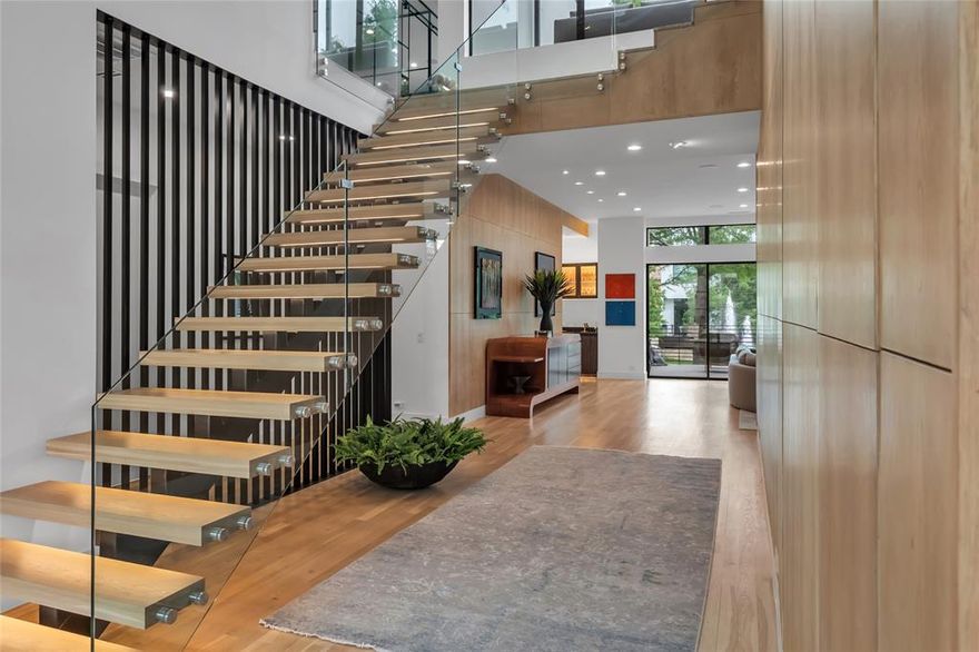 This contemporary masterpiece just underwent a full design-forward renovation that epitomizes modern luxury and optimizes the lakeside view from every room. From the moment you enter the custom steel and glass front door, you're surrounded by stunning views and architectural details – floating glass staircase, louvered steel walls, white oak floors, floor-to-ceiling glass wine cellar, exotic wood cabinetry, glass walls, designer lighting, three lakeside lounging terraces, water wall with Yuri Zatarain sculpture, and more. Main floor primary suite features stunning water views, fireplace, spa bath with heated Terrazzo floors and steam shower, and custom dressing closet. Upstairs is equally impressive with a glass-walled office, gym, and TV lounge with fully equipped wet bar off an expansive terrace with gas fire pit. An elevator and turfed landscaping add ease and convenience. This gated, boutique community marries the best of luxury city living and a lock-and-leave lifestyle.