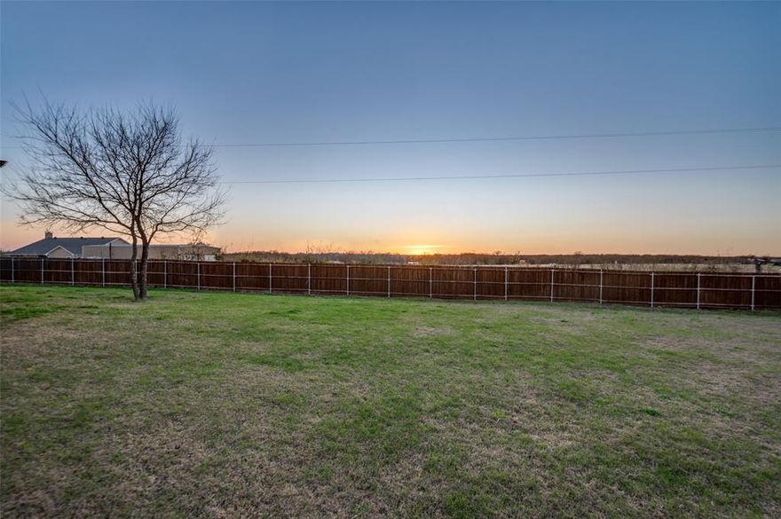 Built in 2023 and positioned at the end of a cul-de-sac on an oversized .36-acre lot, this home offers the kind of space, privacy, and setting that are becoming harder to find. NO HOA! NO MUD or PID taxes! Spend evenings on the covered porch taking in incredible sunset views over the field behind. Enjoy the calm that comes with having room to breathe! 

Inside, warm wood-tone LVP flooring stretches past the built-in mudroom bench into an open living space anchored by a striking wood-burning fireplace, creating a natural place to unwind or entertain. The kitchen is designed to keep everyone connected, featuring a large granite island, walk-in pantry, and abundant cabinetry. The bright eat-in dining area ties the space together with a statement fixture that adds just the right amount of style.

The primary suite is set apart from the rest of the home and overlooks the backyard, giving the space a peaceful, tucked-away feel. The ensuite bath invites you to relax with a deep soaking tub, separate shower, and a generous walk-in closet. 

Step outside to a backyard that truly sets this home apart — fully fenced, irrigated, and wide open, offering the freedom to play, garden, create a pool oasis, or simply lounge on the patio while the sky fades into color each evening. 

Located with easy access to I-35, Denton, and nearby downtown shops and dining, this Krum, Texas home blends newer construction, a premium lot, and small-town charm in a way that feels both comfortable and hard to replicate.