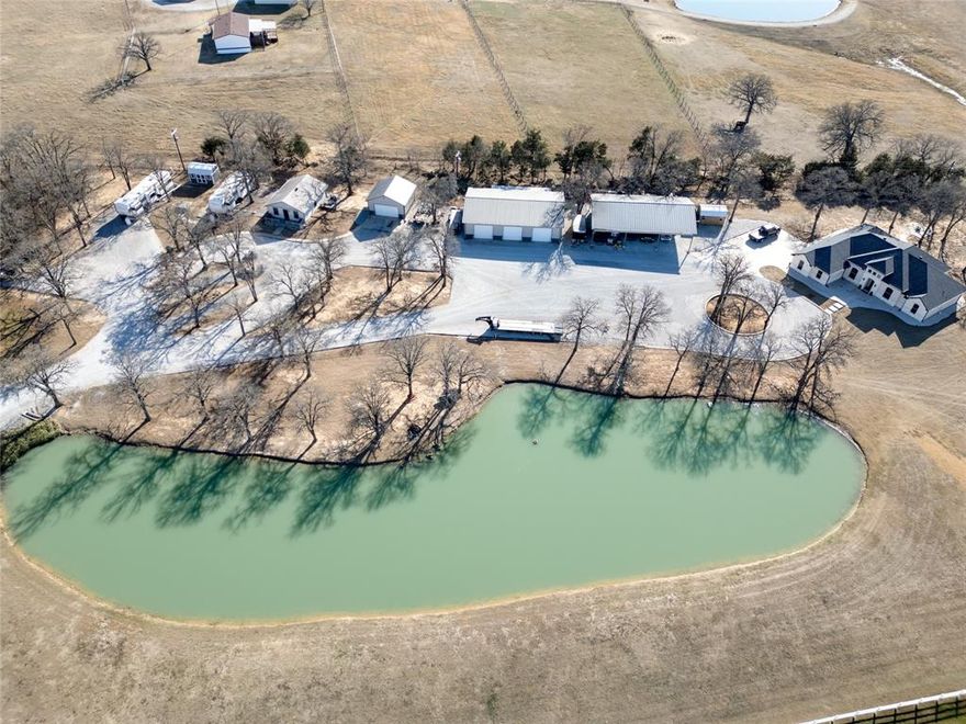 Exceptional custom estate on 5.48 acres offering picturesque views of the scenic pond with fountain, custom home, 2 shops, 6 car space carport, a private guest home, RV Hookups and storm shelter. Perfect property to live, work and entertain in one place. Well-designed custom home featuring 3 bedrooms, 2.5 baths, a two car garage, open living space, chefs kitchen and office. Stunning Chefs kitchen showcasing custom cabinetry, granite island, ambient above and under cabinet lighting with sleek modern light fixtures.  Serene primary suite with tray ceilings, recessed lighting paired with a spa like bathroom offering a walk in shower, relaxing garden tub and spacious closet. Expansive open-concept living space flowing effortlessly into the formal dining area, ideal for gatherings and entertaining. Office with built in desk, upper and lower cabinetry. Utility room with upper and lower cabinets and a full size washer and dryer area. Beautiful wood flooring, granite counters and modern light fixtures throughout. One of kind property, completely fenced and gated. Easy commute to the DFW Airport. Close by shopping and restaurants. Whitesboro ISD or Choice of school.