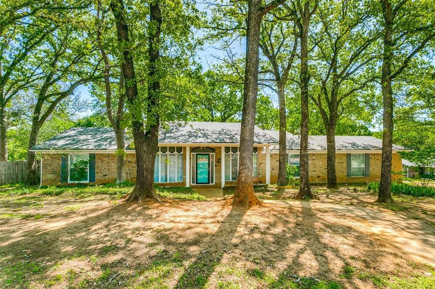 Welcome to your little slice of heaven in the middle of the metroplex. This home is situated on a large corner lot, in a quiet, heavily treed neighborhood with easy access to 183 Hwy. This is the largest lot and sq footage you will find, for this price point, in this area. It is by far the most bang for your buck!Walking up you will notice the great curb appeal, recently painted exterior with a covered front porch. Once in the home you will see updated wood laminate flooring. The front room, off the entry, is the formal living and dining area with a bay window and a great view of the neighborhood. Stepping into the large den you can imagine cozy evenings or your morning coffee snuggled by the fire with a clear view of the backyard. This home has a fantastic eatin kitchen with plenty of cabinet space, countertops and breakfast nook. All of the bedrooms are a great size with spacious closets but...the primary bedroom is everything you are looking for. This large bedroom has a ton of natural light, walkin closets and the bathroom retreat you deserve! It is a spa day, treat yourself, shut off from the world, kind of vibe. It will not disappoint! With the oversized corner lot, the backyard is waiting for an owner who loves to garden and be outdoors. It is perfect for kids and pets. This home is being sold As Is and the price has been adjusted to reflect that. Some of the flooring in the den was damaged by an Air conditioning leak. The leak has been fixed but the flooring needs to be tended to. Seller is willing to have flooring fixed with an acceptable offer.