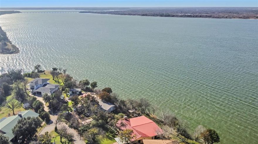 Lakefront living on Lake Whitney at its best—this true lakefront home offers easy access to the water and sweeping views that can be enjoyed from the expansive deck and hot tub, making it ideal for both everyday living and entertaining. Featuring 4 bedrooms and 2 bathrooms, the layout provides comfort and privacy with the primary suite situated away from the secondary bedrooms. The kitchen was remodeled in 2015 with custom cabinetry, granite countertops, a gas cooktop, and double ovens, and the home also includes a dedicated bar area with lake views, perfect for hosting guests. Extensive updates include a standing seam metal roof (2015), vinyl plank flooring (2016), two-zone HVAC heat pump system (2018), sprinkler system (2018), hot water heater (2019), and a bathroom remodel (2019). Located on a dead-end road, this well-cared-for property delivers privacy, functionality, and a lifestyle that’s hard to match, and with STRs in the area, the possibilities here are truly endless—this may be one of the best views in Whitney.