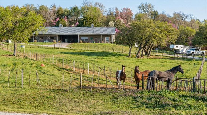 Incredible nearly 10 acre equine property in the sought after Horsemans Ranch subdivision, just 15 miles north of Stephenville, offering breathtaking views and exceptional horse facilities.
This well designed barndominium features a desirable split bedroom floor plan with 3 bedrooms and 2 bathrooms. The spacious primary suite includes a versatile flex space perfect for a private office, nursery, or sitting area. A loft area, currently used as an office, offers flexibility and could easily serve as a third bedroom. The open-concept layout seamlessly connects the generous kitchen, living, and dining areas, creating an inviting space for entertaining. Additional highlights include a large laundry room and an attached carport or shop area for added convenience.
The thoughtfully designed barn area includes three stalls, two with attached runs. One stall can easily be converted back into a fourth stall if desired. A dedicated tack or storage room provides ample space for equipment. The property also features two traps with one equipped with water and a loafing shed, and the other offering two additional stalls.
Completing this equine enthusiast’s dream is access to two community arenas, including one covered arena which is ideal for riding during the hot summer months.