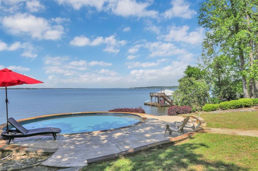 This amazing, contemporary, serene, waterfront paradise awaits with new improved pricing!! Mature shade trees and idyllic landscaping surrounds this home with privacy not found in most lake front subdivisions. Enter to stunning unobstructed open water lake views. Custom built, this home exudes a clean modern feel with open living-dining-kitchen on the main floor. The kitchen is so well laid out with modern stainless appliances, granite counters, a long bar and water views. There is unbelievable storage, plus a butler’s pantry! The first of two screened porches is accessible from the kitchen. The open living concept allows unsurpassed views of the lake with an anchor wall with a wood burning fireplace and built ins. From here walkout to an elevated deck for outdoor living space. This main level elevation includes the primary suite with an office-library which has ceiling to floor shelving, a wood burning fireplace and its own private deck and garden. Pass through to a his-and-hers walk in closet with built-ins and a spa like bath with water views and skylights. The primary bedroom will stun you with the expanse of lake around you. Upstairs are two bedrooms with balcony access facing the lake, an additional balcony off the hallway faces the yard, there's a full bath and two large storage rooms. Downstairs is a full apartment which could also be used as a game room with a full bath and kitchenette opening to a second screened porch as well as the saltwater pool. In the yard you can access the climate controlled workshop. Stroll through the beautifully landscaped yard past the firepit toa boat house with boat and jet ski lifts, a storage room and a waterside party room. There's nothing else quite like this property! A private retreat!!! Call to schedule your private showing and be enjoying this retreat by summer!