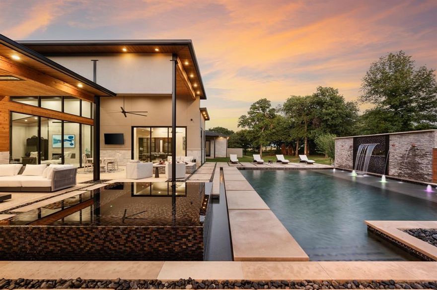 Experience modern luxury on 2 private acres in prestigious Hat Creek Estates in Bartonville. Surrounded by mature trees, this single-story architectural estate offers 13,927 square feet under roof, blending sleek contemporary design with warm natural elements. A dual gated entrance and circular drive create a dramatic arrival.

Inside, soaring ceilings, cedar accents, and walls of glass seamlessly connect indoor and outdoor living. The open-concept layout centers around a striking stone fireplace and a chef’s kitchen featuring a natural stone island, Sub-Zero refrigerators, Wolf gas range, dual dishwashers, wine cooler, hidden butler’s pantry, and wet bar. Accordion glass doors open to a resort-style backyard with a pool, water features, and multiple lounge and dining areas. A game room and media room complete the entertainment spaces.

The primary suite is a private retreat with dual walk-in closets, a spa-like bath with separate vanities and dual showers, an exercise room, and a laundry room with direct closet access. Car enthusiasts will appreciate the 8-car garage with Tesla charging, plus dedicated RV and boat parking.

A detached 1,755-square-foot guest house offers 2 bedrooms, 2 baths, a full kitchen, and private living spaces—ideal for guests or multigenerational living.

Thoughtfully equipped with Savant whole-home automation, a 16-camera security system, lightning protection, Kohler generator, safe room, designer lighting, and a 2024 Class IV impact-resistant roof, this estate delivers exceptional quality and functionality.

A rare offering combining privacy, design, and resort-style living in the heart of Bartonville.