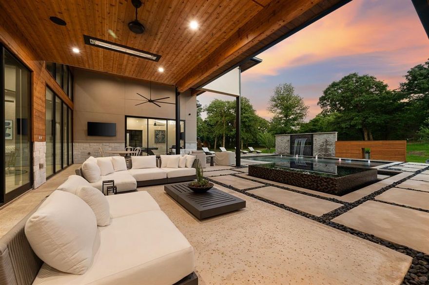 Priced to encourage strong interest.  Experience modern luxury on 2 private acres in the prestigious Hat Creek Estates of Bartonville, Texas. This single story architectural masterpiece blends sleek contemporary design w warm natural elements, offering an inviting yet sophisticated retreat behind a gated entrance and circle driveway that leads to a grand entryway. Inside, dramatic ceilings, cedar-paneled accents, and expansive walls of glass create a seamless connection between indoor and outdoor living. The open-concept layout showcases a stone fireplace in the living room and a chef-inspired kitchen featuring a dramatic natural stone island, built-in wine cooler, dual dishwashers, hidden butler’s pantry, Sub-Zero refrigerators, Wolf gas range, and wet bar. Accordion glass doors open to the backyard oasis, where resort-style amenities include a sparkling pool, cascading water features, and multiple lounge and dining areas for gatherings. A game room opens directly to the patio area, while the nearby media room offers an ideal space for movie nights or game-day viewing. The luxurious primary suite is a private sanctuary with his-and-her walk-in closets, a spa-like bathroom featuring dual shower heads, separate vanities and an exercise room off the primary bath, with the laundry room conveniently connected to the walk-in closet. Car enthusiasts and adventurers alike will appreciate the impressive 8-car garage w a Tesla charging station and dedicated RV-boat parking. The detached 1,755-square-foot guest house—located off the RV garage—includes 2 bedrooms, 2 bathrooms, walk-in closets, its own living and dining area, and a full kitchen, perfect for extended family or guests. Every detail of this home exudes sophistication and comfort, from designer finishes throughout to its thoughtful layout designed for seamless living and entertaining. With its refined craftsmanship, privacy, & resort-style amenities, this estate represents the pinnacle of Bartonville luxury living.