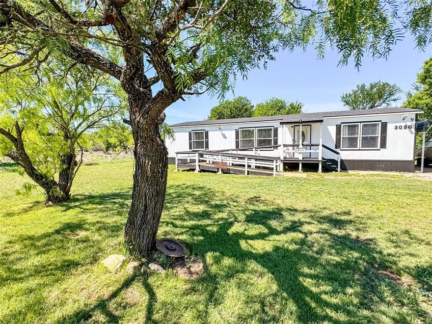 Welcome to this beautifully updated 2015 double-wide located in Harbor Point, where you’ll enjoy access to community amenities including a boat ramp, dock, pool, and trash service—perfect for lake living. This 3-bedroom, 2-bath home offers a spacious open-concept layout with the living room and kitchen flowing seamlessly together, creating an inviting space for both everyday living and entertaining. The home has been thoughtfully updated throughout with new flooring, fresh paint, and modern finishes, including updated bathrooms with new vanities, sinks, and toilets, and a primary suite featuring a brand-new walk-in shower. The kitchen has been enhanced with stylish butcher block countertops, adding warmth and character, while large windows bring in an abundance of natural light. Outside, you’ll find a covered front porch with ramp access, a back porch for relaxing, a two-car carport, and a powered storage building that would make a great workshop. The roof was replaced in 2025, and the property also includes five exterior security cameras that will convey, along with 30 and 50 amp RV hookups ready to be connected. Mature trees provide shade and a peaceful setting where deer are often seen passing through, adding to the charm of this well-kept, move-in ready home in a desirable lake community.