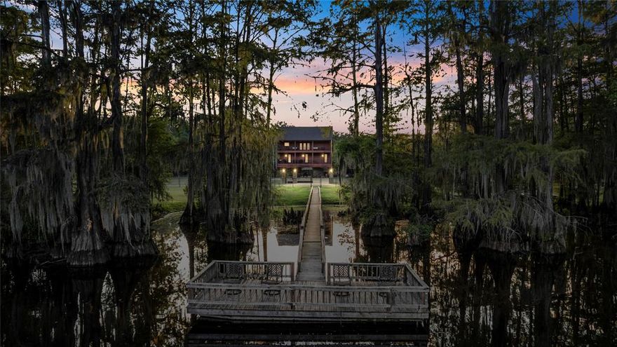 Discover one of the most unique opportunities ever offered on Caddo Lake — a rare combination of waterfront living and unrestricted acreage. This remarkable property includes a beautifully crafted elevated home on a double lot plus 30± acres across the street with a private 7-acre pond, totaling approximately 32 acres of East Texas beauty. A package like this is truly unheard of. The waterfront home is designed for both comfort and durability, featuring an elevator, real wood floors, plantation shutters, and abundant natural light. The spacious kitchen boasts granite countertops, JennAir appliances, custom cabinetry with pull-outs, and a large walk-in pantry. The primary suite offers travertine finishes, double vanities, a jetted tub, and a tiled shower with body sprays. Additional highlights include a cozy living area with a gas-log fireplace, a game room upstairs that could easily convert to additional bedrooms, and a storm-shelter bath with workshop space downstairs. Outdoor living is front and center with expansive porches, a large fire pit, and a private pier extending into deep water (approx. 25–28 ft). Recent upgrades include rebuilt exterior concrete stairs and pier, ensuring years of worry-free enjoyment. The home’s spray-foam insulation and dual HVAC systems provide energy efficiency and comfort year-round. Across the street lies the true showpiece: 30 acres of unrestricted land with a private, named 7-acre pond, surrounded by woods and trails. Perfect for fishing, hunting, or simply enjoying nature, this acreage offers endless possibilities for recreation, development, or creating your own private retreat. From sunrise views over the water to peaceful walks around the pond, this property offers a lifestyle rarely found in East Texas. Whether you’re seeking a family retreat, a legacy property, or a one-of-a-kind recreational escape, this Big Cypress Bayou estate delivers it all.