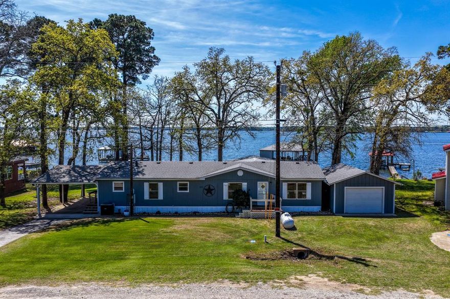 Welcome to 23351 Wateridge Loop, a stunning 160' of waterfront FULLY FURNISHED retreat thoughtfully designed for seamless indoor-outdoor living & unforgettable lakefront sunsets. Perfectly positioned on the lot, the home captures breathtaking views from the expansive 16’x30’ covered back patio, added in 2023 & fully equipped for entertaining. Enjoy comfortable seating, a fire table, dining area, recessed lighting, mounted bug zappers, & a 55” smart TV—all included. Inside, a striking 15’ three-panel sliding glass door opens completely into itself, creating a 10’ wide unobstructed opening that blends indoor & outdoor spaces. A collapsible screen allows you to enjoy fresh air while keeping unwanted guests out, offering the ultimate entertaining experience. The home was extensively renovated in 2023 with new appliances, updated kitchen sink, modern shower stalls, a dormitory-style bedroom, & the addition of a third full bathroom with direct patio access—perfect for coming in from the lake. Outdoors, the backyard is designed for relaxation & fun, featuring bistro lighting, a large steel cauldron fire pit with Polywood seating for eight, & a sprinkler system drawing water directly from the lake. Extensive drainage improvements & gutters with leaf guards (2024) provide long-term protection & peace of mind. The boathouse includes two electric lifts—one for a boat up to 24’ & another with a built-in jet ski lift—plus a storage area with a rolling steel window & concrete bar top. Added features include walk-down water access (2025), a Spider Mister system, & a desirable “sugar sand” lake bottom with 2’–5’ depth, ideal for swimming & water activities. Offered fully furnished with most contents included, this turnkey property is ready for immediate enjoyment. Just 15 miles from Tyler, residents enjoy a private boat launch, park, playground, & a new community garden underway. Lake Palestine is renowned as one of East Texas’ premier fishing lakes, hosting tournaments year-round.