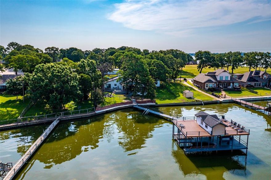 Indulge in luxury living at this stunning waterfront estate in Kemp, Texas. This picturesque 4 bedroom, 2 bathroom lakefront home is equipped with everything you need for a life of ease and relaxation. Take in the serene views from your private boat dock and boat house or unwind on the expansive wooden deck with ample seating and a pergola-shaded dining area. Indulge in a cozy evening by the firepit with rockscaping. Inside, you'll find luxury vinyl plank flooring, an open concept living area with brick fireplace, and a chef's kitchen with a coffee bar, granite counters, beautiful backsplash, and stainless-steel appliances. The owner's suite offers a fantastic en-suite with a walk-in shower with pebble flooring, and an exterior sliding door leading to a patio overlooking the lake. With two additional spacious bedrooms, another full bath, and a bonus room offering lake views with a vaulted ceiling, this exquisite property is the epitome of luxury lakefront living.