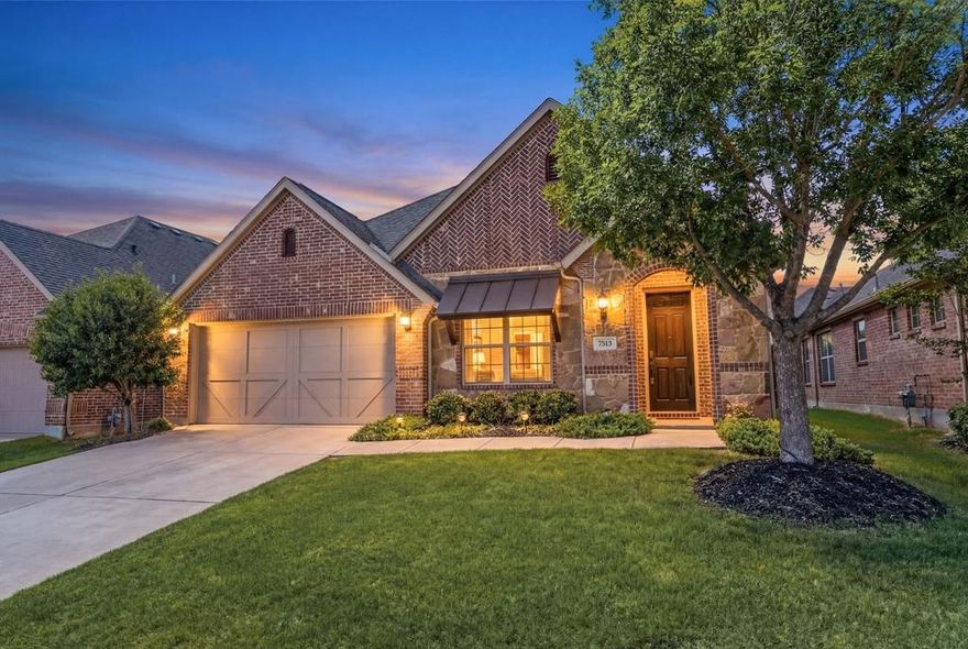 Exquisite single-story, energy-efficient home in the master-planned community of Trinity Falls in North McKinney. Lush trees and manicured landscaping frame the striking brick and stone façade, highlighted by a distinctive herringbone detail and elegant copper window awning, while an arched entry leads to the inviting brick front porch complete with a Ring doorbell and keyless entry. Inside, a dramatic circular foyer with tray ceiling and statement lighting sets the tone. Engineered wood floors flow throughout the main living areas. A versatile front bonus room—ideal as a home office, media, or game room—is wired with a Denon smart-home sound system for listening to music or watching the big game with surround sound. The private primary suite, accessed through French doors, features vaulted ceilings, four sunlit windows, custom built-in shelving, a sitting area, and two generous walk-in closets. End a long day in the spa-inspired bathroom, which offers dual sinks with granite countertops, a soaking tub beneath a large window, a walk-in tile shower with body spray, and a private water closet. Enjoy cooking and baking in the eat-in kitchen that boasts white cabinetry with deep drawers for pots and pans, granite countertops, tile backsplash, walk-in pantry, and an island with undermount dual sink and upgraded pull-down faucet. Host dinner parties or family meals in the light and bright dining area and gather your loved ones in the cozy living room, anchored by a gas fireplace and vaulted ceilings, with patio access for seamless indoor-outdoor living. The covered patio is an entertainer’s dream, showcasing a vaulted tongue-and-groove pine ceiling with fan, in-ceiling speakers, and gas stub in place for outdoor grilling. A spacious backyard with grassy play area completes the setting. Community amenities include pools, trails, ponds, dog park, pickleball, playgrounds, Frazier Elementary, and easy access to Hwy 75, HEB, and Buc-ee’s.