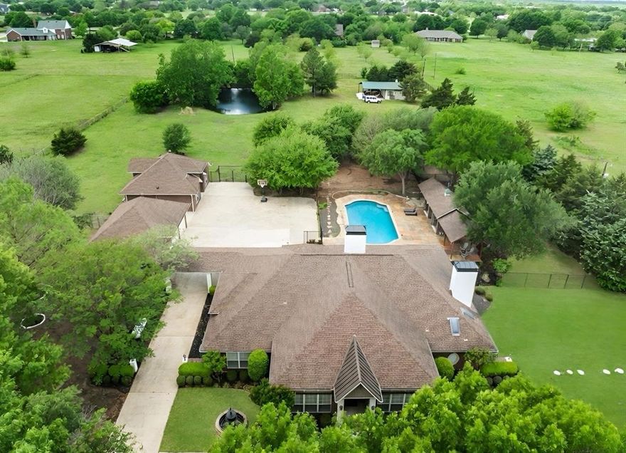 Set on 3.54 beautifully treed acres in sought-after Lovejoy ISD, this exceptional Fairview estate offers privacy, luxury, and flexibility with a large PebbleTec pool, separate guest house, detached 3-car garage, insulated shop-barn, seasonal pond, and horse-friendly grounds. The main residence features handscraped hardwoods, fresh interior paint, updated lighting, plantation shutters, formal living and dining, dry bar with wine refrigerator, butler’s pantry, private study with built-ins, and a chef’s kitchen with granite countertops, oversized island, dual copper sinks, and premium stainless built-in Viking appliances, including a commercial-grade 8-burner gas cooktop and double ovens. The family room includes vaulted ceilings and a cut-stone wood-burning fireplace with gas starter. The primary suite offers a sitting area and direct outdoor access, while the renovated bath features marble finishes, a freestanding soaking tub beside a see-through fireplace with gas logs, frameless glass shower, dual vanities, and cedar closet. A separate wing includes a game room, 2 bedrooms, and 2 updated baths. Approximately 90 feet from the main home, the separate 1,080 SF guest house includes a recently added  luxury kitchen, updated bath, walk-in pantry, and spacious his-and-her walk-in closet, ideal for guests, multigenerational living, or a mother-in-law suite. Rear parking accommodates 6+ vehicles. The insulated 20' x 20' shop-barn includes a large electric roll-up door and extended covered concrete pad. Recent improvements include 2 newer energy-efficient HVAC systems in the main house (4-ton in 2024 and 5-ton in 2025). Main house, guest house, and detached garage are all built with steel framing, including steel wall studs and steel roof trusses.