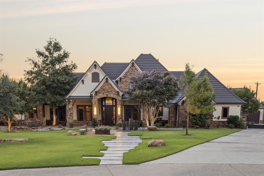 Contemporary generational living on 2.07 unincorporated acres in Argyle! Built in 2014, this 4,639 SF, 4 bed, 5 bath showcases polished concrete & terrazzo flooring, soaring ceilings with exposed beams, a floating staircase, and a dramatic onyx clad fireplace anchoring the open living & dining area. Chef’s kitchen with oversized island, attached breakfast table, farmhouse sink, designer lighting, and built-in espresso. The primary suite opens by sliding door to the backyard and features a pergola covered jacuzzi. Whole-home perks: Control4 smart-home system, security, tornado shelter, central vacuum, media room, fitness room, and upstairs & downstairs laundries. Outdoor living rivals a luxury hotel with the lap pool, hot tub off the primary, covered outdoor kitchen with gas grill + Big Green Egg, pergola dining & lounge spaces. Parking and hobbies are a dream with a 4 car attached garage + gated motor court and a detached 8 car mechanics garage with guest quarters (two living areas, wet bar, full bath). Sale includes the fully fenced, unimproved 1-acre parcel behind the home (total 2.07 acres). Minutes to shopping & dining; Argyle ISD and near Liberty Christian.