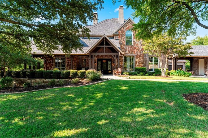 Nestled in one of McKinney’s most exclusive gated communities, this timeless residence offers a perfect blend of elegance, comfort, and luxury. A true private oasis, it seamlessly integrates indoor and outdoor living spaces. The rare wraparound front porch provides a peaceful setting to enjoy views of a nearby pond and fountain. Ideal for relaxing or entertaining, the backyard features a resort-style pool and spa, complemented by an expansive outdoor living area with a built-in grill, refrigerator, fireplace, and TV connection. Surrounded by lush vegetation, the space offers exceptional privacy. Walk thru the front door and the home greets you with a view through to the rear property. To the right, a cozy formal living room with a fireplace flows into the dining room. To the left, a Texas-style home office with double doors leading to a patio with stunning sunset views. The great room, with wood beams on the ceiling and a two-story stone fireplace, overlooks the backyard through large windows that flood the space with light. The chef’s kitchen features a built-in SubZero refrigerator (2025), double ovens, two dishwashers, a gas cooktop, microwave, and a pellet ice maker. A massive island with a separate vegetable sink provides ample meal prep space. The spacious primary suite opens to the backyard and includes a luxurious bath with a jetted tub, separate shower, and custom closet system. Upstairs, a media room and game room are complemented by three bedrooms, each with an en-suite bath. Two oversized garages are accessible via a porte cochere. The home features speakers wired inside and outside of the home, hand-scraped hardwood floors, travertine in the kitchen and breakfast area, and carpeting in the bedrooms. Roman shades and custom draperies elevate the home’s refined atmosphere. This stunning home blends exceptional craftsmanship with modern amenities, offering an unparalleled lifestyle of luxury and privacy in one of McKinney’s most prestigious communities.
