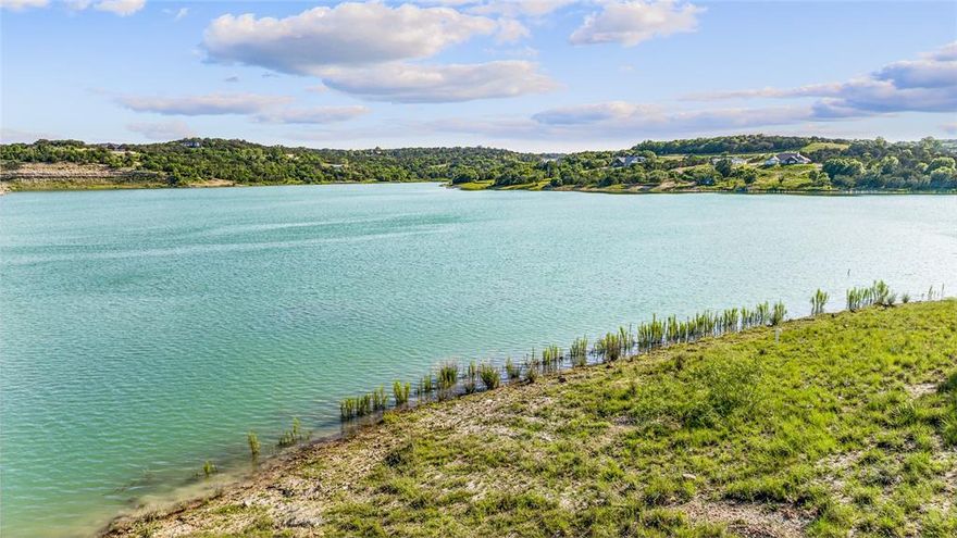 Stunning Lakefront Custom Home with Panoramic Views! Discover the perfect blend of luxury and relaxation in this exceptional lakefront property, nestled on the shores of a 100-acre private lake in the coveted Mountain Lakes community. Designed with entertaining in mind, this gorgeous custom home features a spacious open-concept layout and an expansive back patio that offers breathtaking views of the water and surrounding Hill Country.
Step into the inviting living room with its soaring ceilings and impressive stone fireplace—ideal for cozy evenings and memorable gatherings. A wall of windows floods the space with natural light and captures the serene lake vistas. The beautifully appointed kitchen is a chef’s dream, complete with granite countertops, a center island, farmhouse sink, pot-filler, and walk-in pantry.
Retreat to the primary suite, designed to take full advantage of the lake views, offering a peaceful escape at the end of the day. A dedicated home office on the main floor provides convenience for remote work. Upstairs, you’ll find a second spacious living area with access to a large covered deck—perfect for enjoying your morning coffee or sunset cocktails while soaking in the million-dollar views. Two additional bedrooms share a Jack-and-Jill bathroom, making this home ideal for family or guests.
Follow the gentle path down to the shoreline, where you can fish, kayak, or swim in the crystal-clear waters. Residents of the Mountain Lakes community also enjoy access to premium amenities including a clubhouse, pool, boat ramp, fishing dock, playground, BBQ area, and RV storage.
Don’t miss this rare opportunity to own a piece of lakeside paradise!