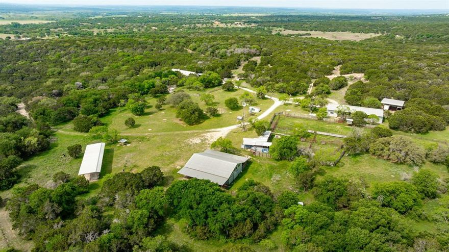 This 400-acre property in Hamilton County offers a unique opportunity for investment, recreation, or residential use in the heart of Hamilton, Texas. Formerly a working bison ranch, it carries both character and legacy. Located just 13 miles from Hico and Hamilton, the property is easily accessible to dining, shopping, and medical services. Approximately 400 acres lie west of Highway 281, with an additional 106 acres available east of the highway. Both tracts feature Highway 281 and CR frontage.

The main entrance, with custom stone gates, leads to a distinctive stucco lodge designed for entertaining. The lodge features a massive great room, vaulted ceilings, an open kitchen and dining, a loft with a full bath, a primary suite with a kitchenette and private entrance, plus a guest room and laundry. Downstairs offers another large kitchen and suite, full bath, and half bath, ideal for gatherings or family retreats.

Outside, improvements include a large metal workshop, cattle pens, barns, and an original windmill. The scenic terrain features rolling land, hardwoods, and a stock tank for livestock and wildlife. A separate entrance off CR 105 leads to an area featuring large oaks, a water well, an RV hookup, and electricity, ideal for a future homesite or weekend getaway.

With versatile improvements, extensive road frontage, and infrastructure, this property is well-suited for a hunting lodge, family compound, or long-term investment.