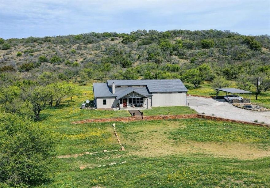 Barndominium on 35.959 Acres – Refined Country Living Near Graham

Just ten minutes from Graham, this exceptional 35.959-acre property offers a rare blend of comfort, land stewardship, and recreational versatility in a highly desirable Young County setting.
A manicured homesite sets the tone, featuring King Ranch drought-tolerant sod in the front yard for a polished, welcoming approach. Mesquites have been selectively cleared to reveal expansive sight lines across rolling native and improved pasture. Two stock tanks enhance both the beauty and function of the land, one thoughtfully improved with a dock and pump system.
The residence is designed for gathering and retreat alike, offering four bedrooms, three full baths, and one half bath. A dramatic two-story vaulted great room anchors the home, complete with a fireplace and expansive windows that frame panoramic views of the surrounding acreage. The open-concept design seamlessly incorporates a spacious dining area and a well-appointed kitchen featuring a new gas range, double ovens, granite countertops, and an eat-at bar that encourages connection and conversation. The layout balances scale and warmth, creating an inviting space equally suited for everyday living or entertaining.
The 35x35 climate-controlled garage extends the home’s versatility, featuring commercial-grade doors and a custom indoor basketball court setup. Whether used for recreation, equipment storage, or workshop space, it reflects the thoughtful functionality carried throughout the property. Additional improvements include two water wells, a private shooting range, fenced dog run, chicken coop, and a Generac generator for added reliability.
Currently under Wildlife Management valuation, the property supports responsible land use while offering meaningful tax advantages.
Wide Texas skies, open pasture, and a home designed for those who appreciate space, privacy, and purposeful ownership.